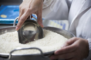 Primer plano de una mano sacando arroz blanco de un recipiente metálico