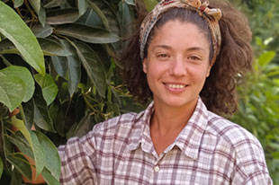 Belén, productora ecológica, junto a un aguacatero