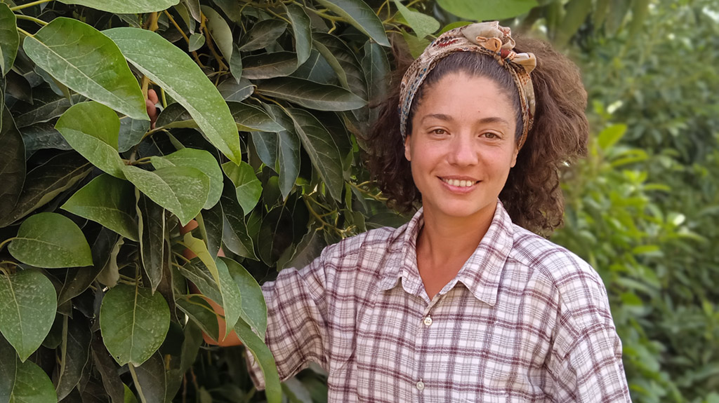 Belén, productora ecológica, junto a un aguacatero