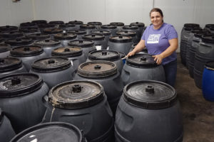 Livia Romance standing next to barrels of olives in a warehouse