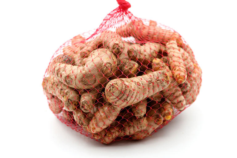 Un sac en filet contenant des rhizomes de curcuma