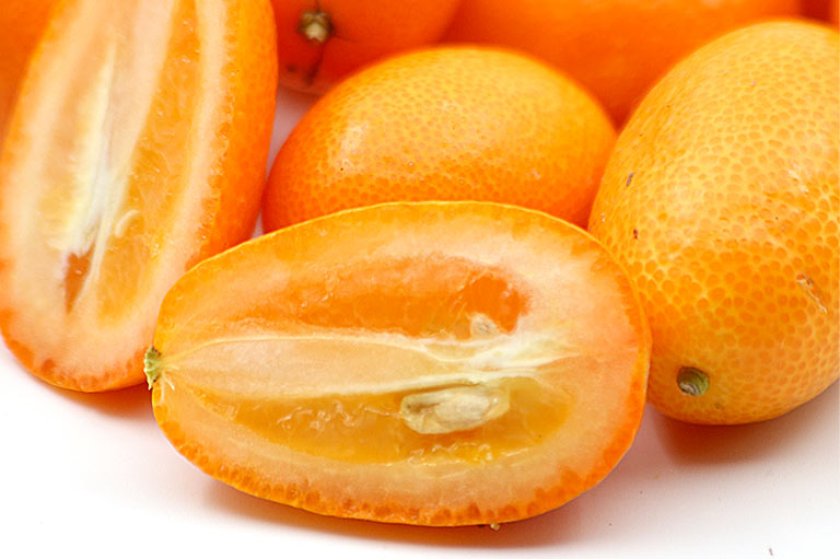 Close up photograph of whole and cut kumquats