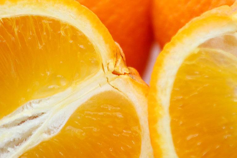 Close up photograph of cut halves of salustiana oranges, showing the thickness of the skin and colour of the segments