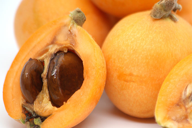 Close-up van een doorgesneden loquat, met de zaden en de textuur van het vruchtvlees
