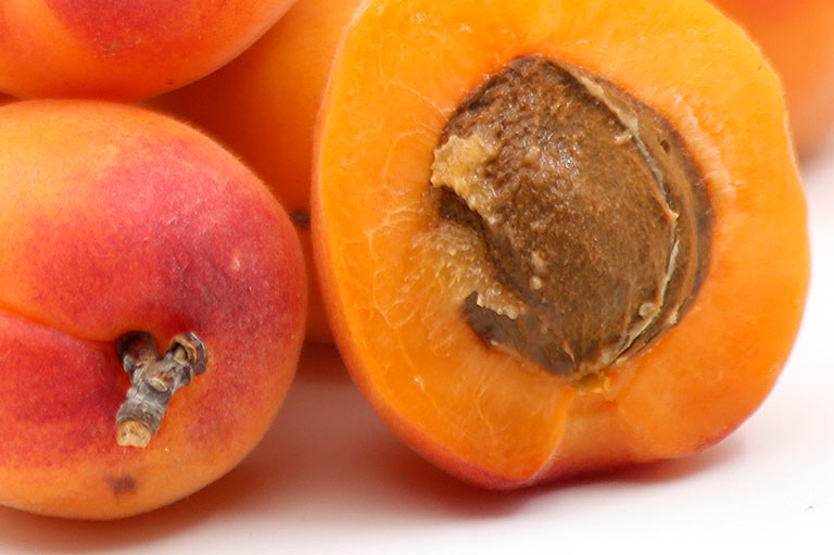Close up van een abrikoos, doorgesneden om het oranje vruchtvlees en de pit te tonen