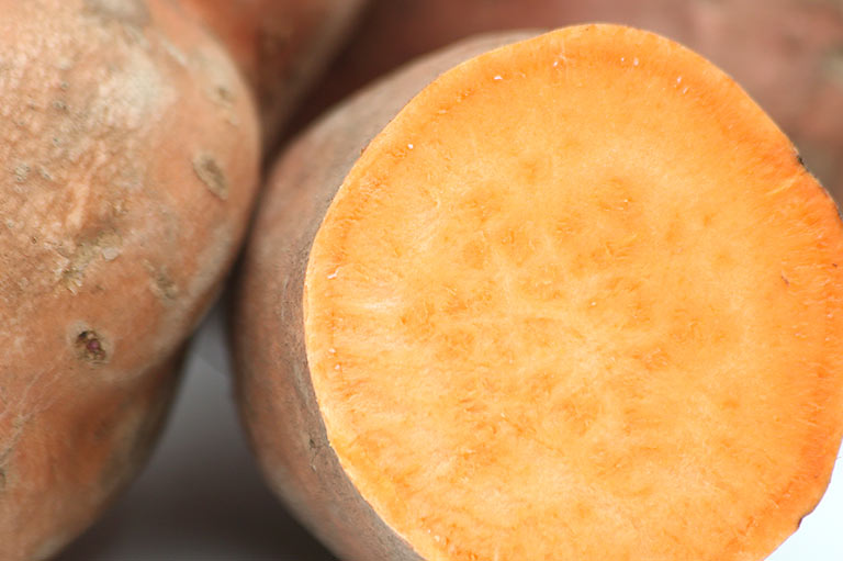Close up of whole and cut sweet potataoes