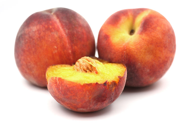 A group of three peaches, one of them cut in half to show the yellow flesh and stone inside