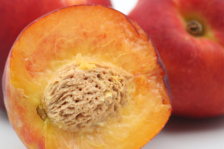 Close up van een doormidden gesneden nectarine, om het oranje vruchtvlees en de pit binnenin te laten zien