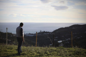 Organic producer David Ruiz standing on his land with a view of the Mediterranean
