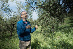 Rafael García staat naast de tak van een olijfboom