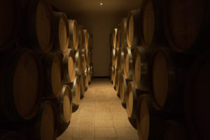 A dark room, full of stacked wine barrels