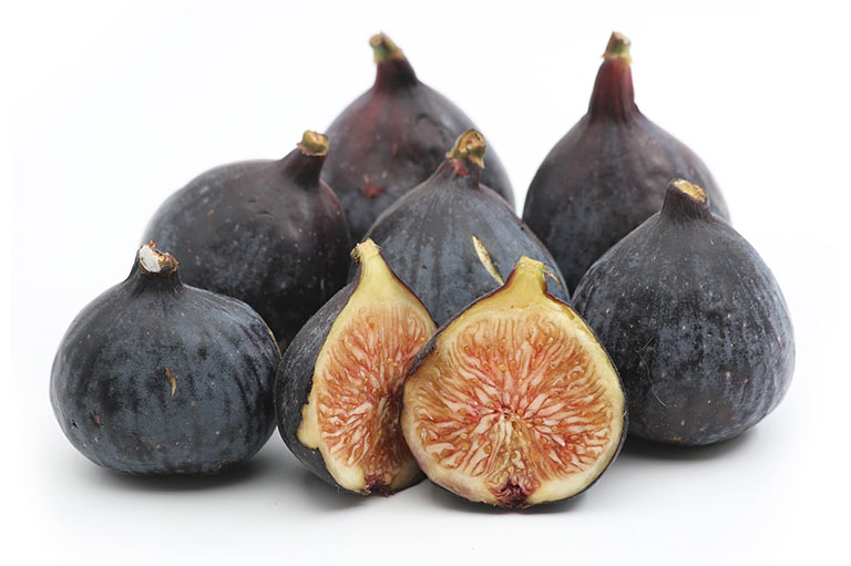 A group of figs with purple skin. Two figs are cut open to show the soft yellow and pink flesh inside