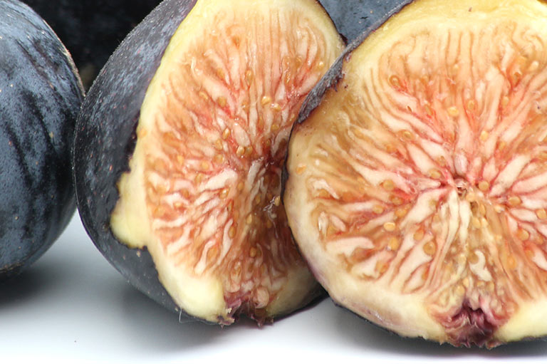 Close up of two cut figs showing the soft yellow and pink flesh inside