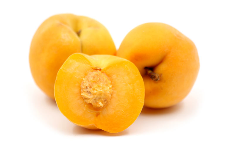Three yellow peaches, showing the orange and yellow skin and bright yellow flesh inside