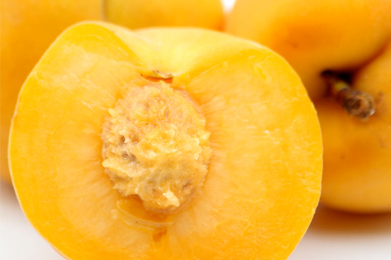Close up of a cut yellow peach, showing the bright yellow flesh and stone inside