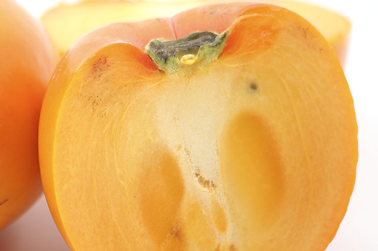 Close-up of a cut Sharon fruit, showing the orange flesh inside