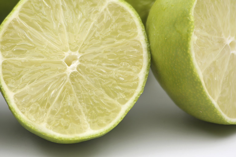 Close-up of a cut lime, showing the green rind and the light green citrus segments inside