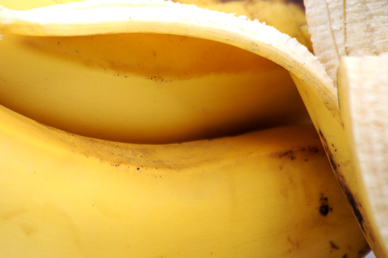 Close up of bananas, showing the distinctive black marks on the yellow skin of the Canary Island variety