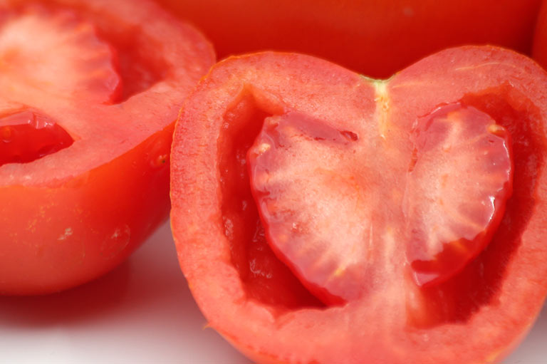 Primer plano de tomates en rama, mostrando las semillas en su interior