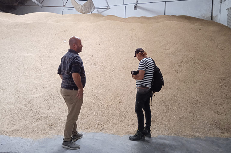 Jose Daniel Carbonell en een bezoeker inspecteren een berg geoogste rijst