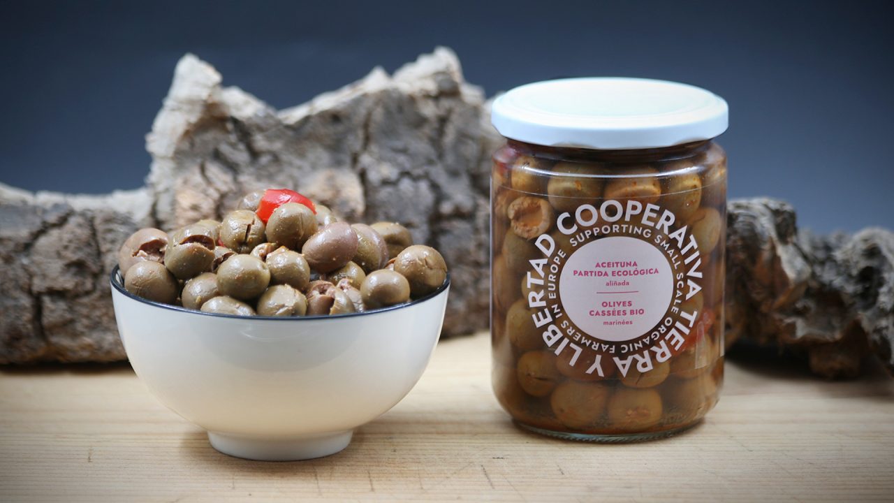 A jar and bowl of olives on a table